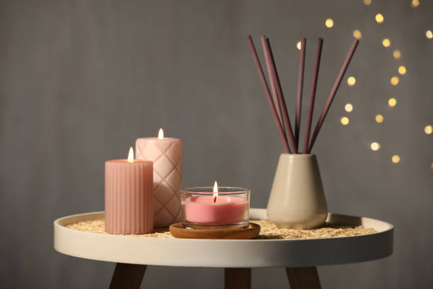 burning candles and reed diffuser on table against grey background - aromatic oil burner imagens e fotografias de stock