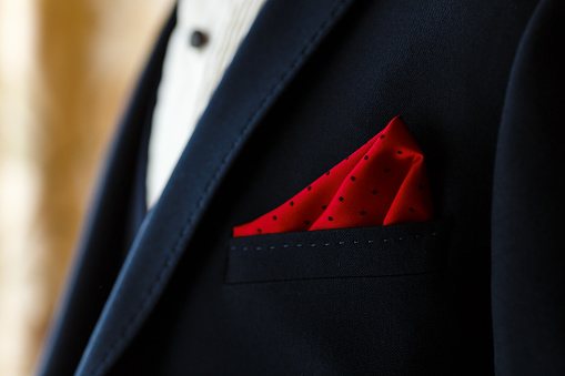 Young groom in dark blue suit with red dotted handkerchief in the pocket. Men's wedding accessories