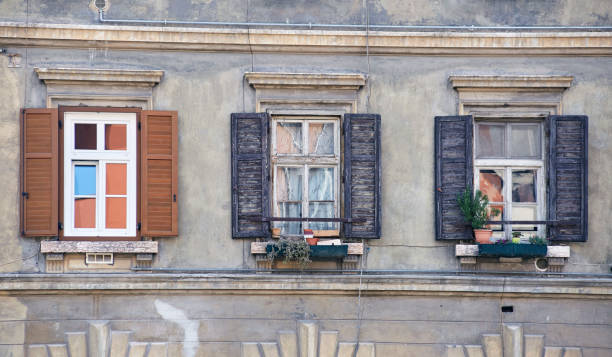 tres ventanas italianas en la antigua fachada de la pared con persianas marrones en mal estado de madera abiertas - wood shutter rusty rust fotografías e imágenes de stock