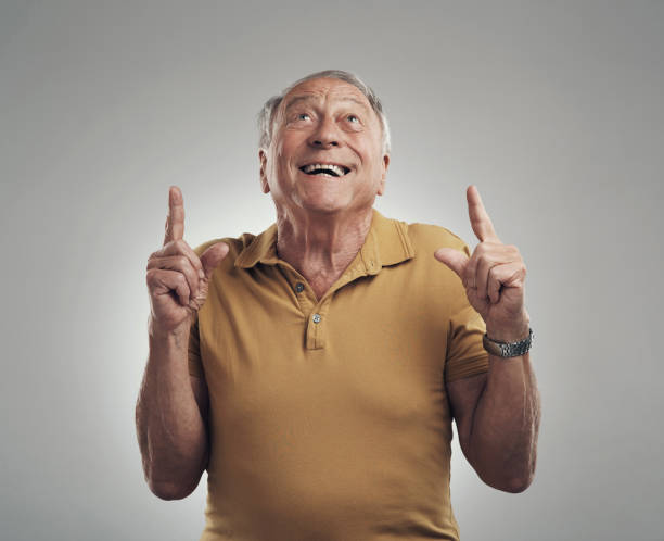 istock Studio shot of an elderly man pointing in at something and smiling against a grey background 1318862007
