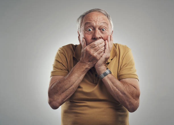 Studio shot of an elderly man getting a big shock against a grey background