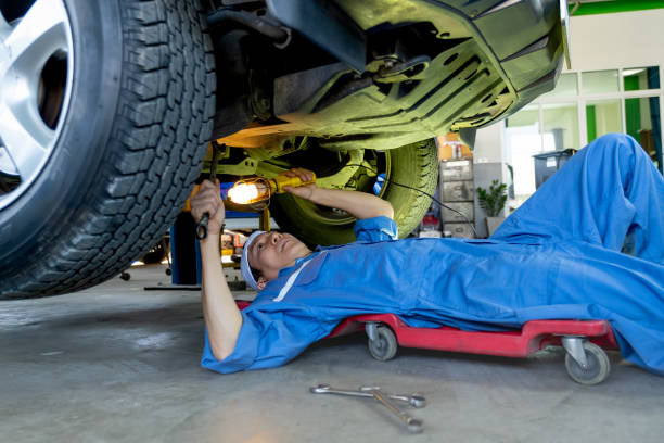 istock Technician or garage worker lie down under the car and use lantern to guide for fix the problem in workplace area 1318863322