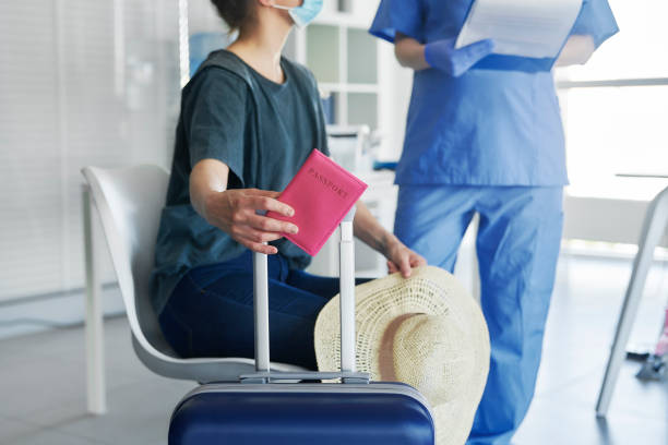 donna da vicino in possesso di passaporto e bagagli durante il test medico - airport screening foto e immagini stock