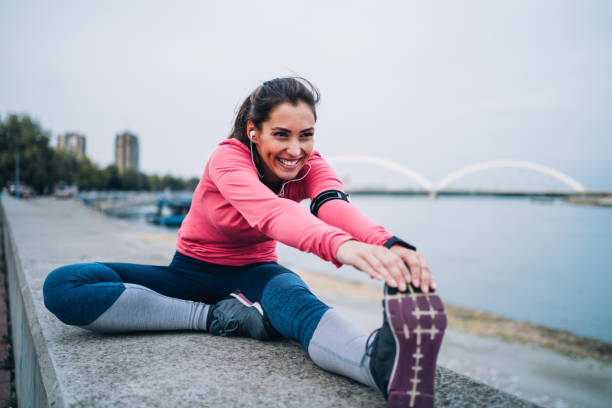 idrottskvinna som sträcker sig utomhus - runner holding legs bildbanksfoton och bilder