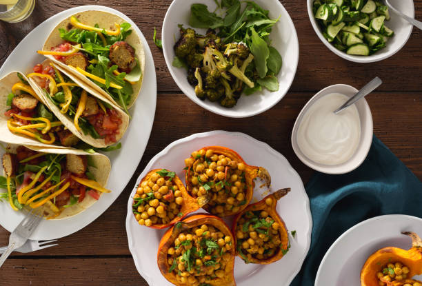 Overhead view autumn dinner table with baked pumpkin with chickpeas curry, tortilla with falafel and salad