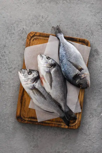 Raw fish dorada or sea bream on cuuting board top view