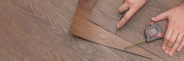 istock Vinyl flooring installation. Easy installation and cutting with a knife, Master cuts vinyl plank before installation, brown heated floor. Copy space 1318870382