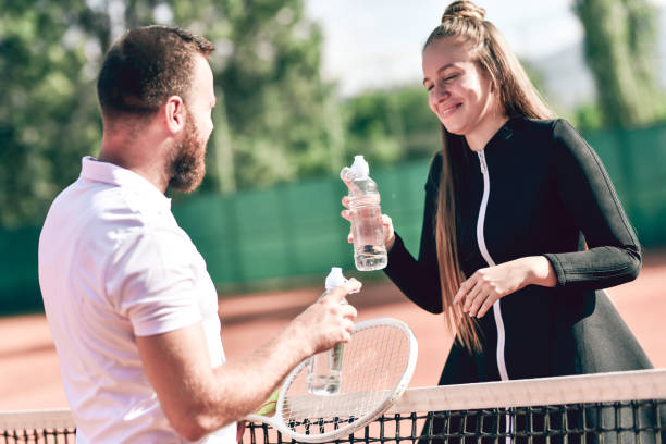 süßes tennispaar trinkwasser in der pause - tennis court love victory stock-fotos und bilder