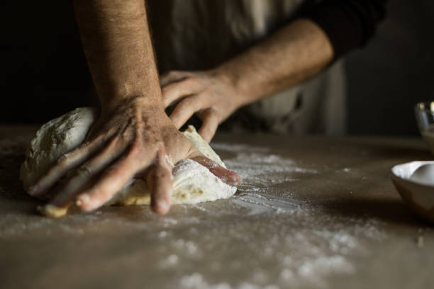istock Male hands kneading dough on the table 1318872490