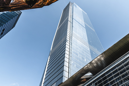Contemporary architectural office building and a fragment the Vessel in Hudson Yards on a sunny day.