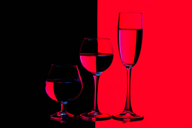 istock Three Different in Height Glass Cups Placed in One Line Against Vivid  Black And Red Background. Horizontal Image Composition 1318874462
