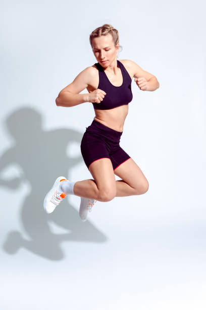 istock Active Caucasian Female Runner in Good Fit During Jumping Exercise On White Background. Vertical Image 1318874494