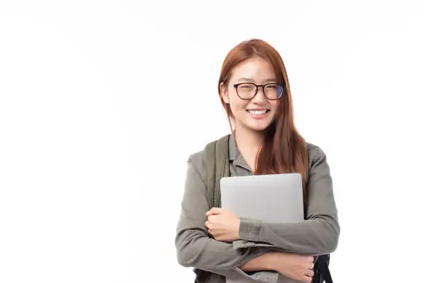 Photo of Portrait of happy casual Asian girl student with backpack and laptop isolated on white background. Back to school and learning concept.
