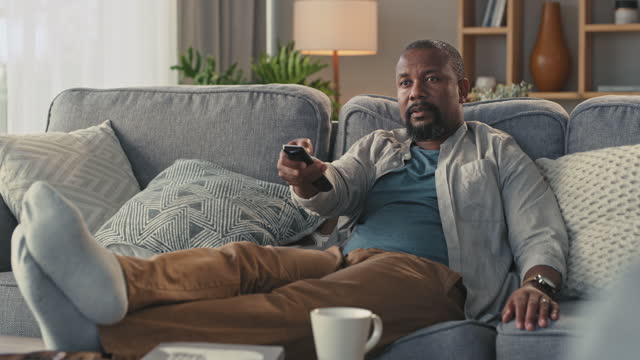4k video footage of a man relaxing on his couch watching tv at home