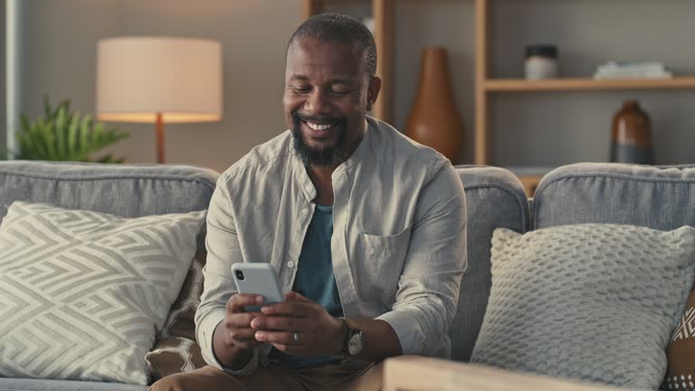 4k video footage of a man relaxing on his couch while using his cellphone to text