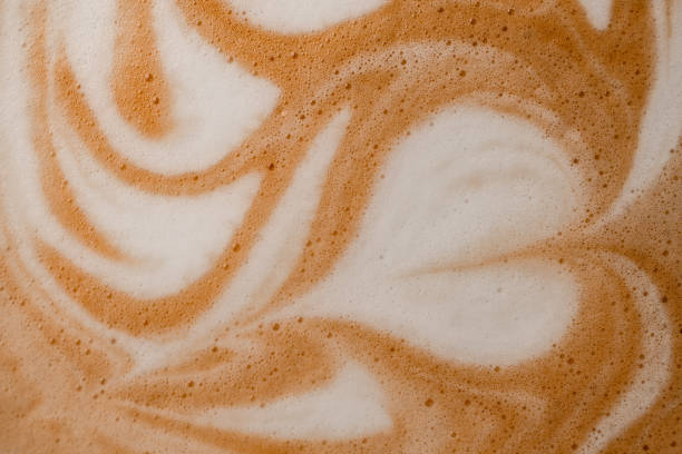 close-up of wonderful white milk patterns on brown foam of coffee drink. - latté imagens e fotografias de stock