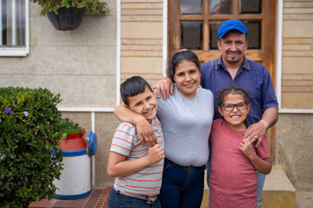 Rural Latin American family in front of their new house Portrait of a rural Latin American family in front of their new house and looking at the camera smiling - housing policy concepts district photos stock pictures, royalty-free photos & images