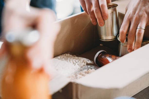 foto de cerca de voluntarios preparando cajas de donación con alimentos en el banco de alimentos y ropa - non perishable fotografías e imágenes de stock