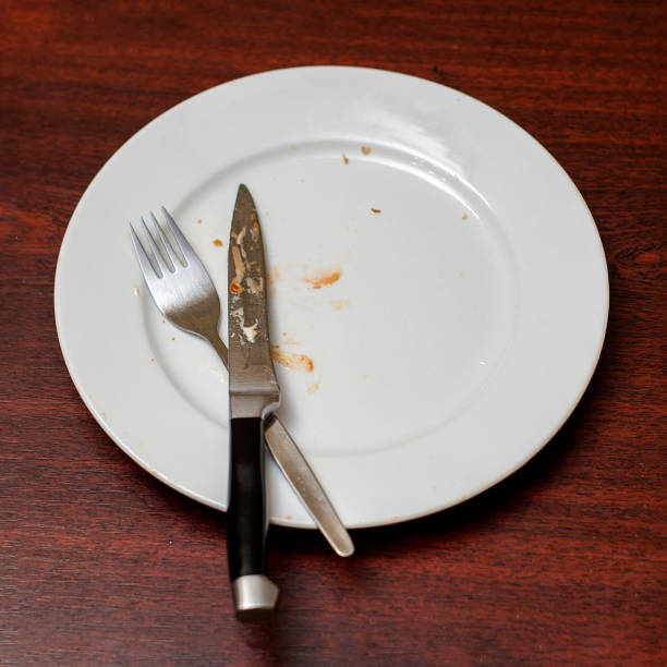istock Dirty plate left after dinner. Knife and fork on a dirty plate. 1318879559