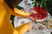 Woman cutting a slice of a strawberry cheesecake