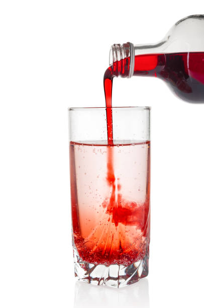 syrop żurawinowy i syrop z czarnej porzeczki wlewający się do szklanki wody na białym tle - pouring liquid syrup red zdjęcia i obrazy z banku zdjęć