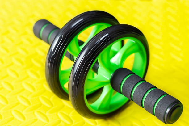 istock Gymnastic roller black and green close-up on a bright yellow background. Abdominal trainer 1318882250