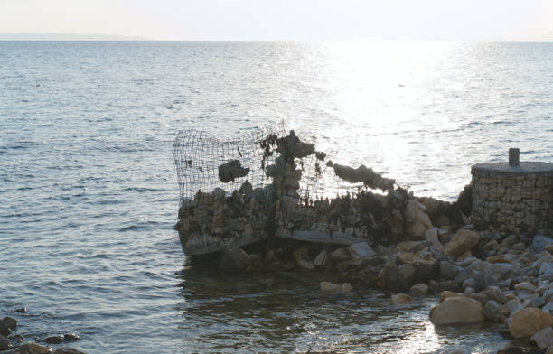 istock Wire and stone installation in the sea with the Sun behind it 1318884006