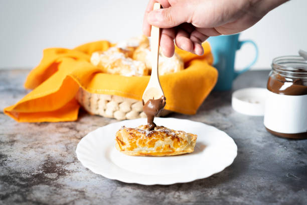istock Man's hand putting chocolate inside a puff pastry with a wooden spoon 1318886724