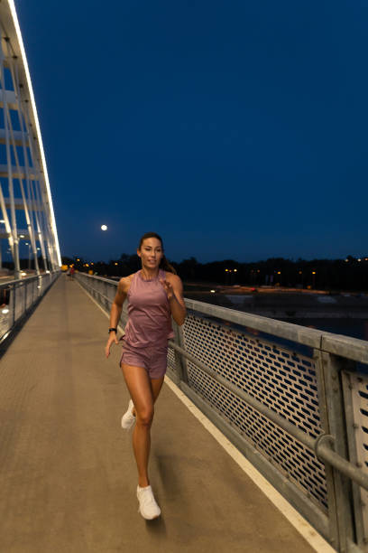 istock Young female athlete running on the bridge at night 1318886741