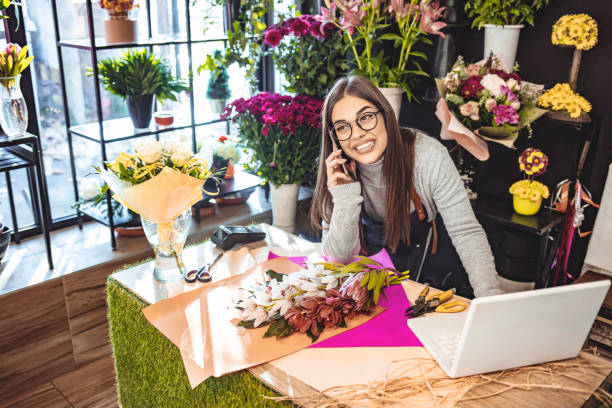 sonriente dueño de floristería trabajando en computadora portátil. - florist small business flower shop owner fotografías e imágenes de stock