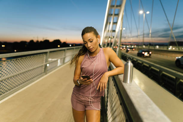 istock Young female athlete standing and using mobile phoneat the bridge 1318887538