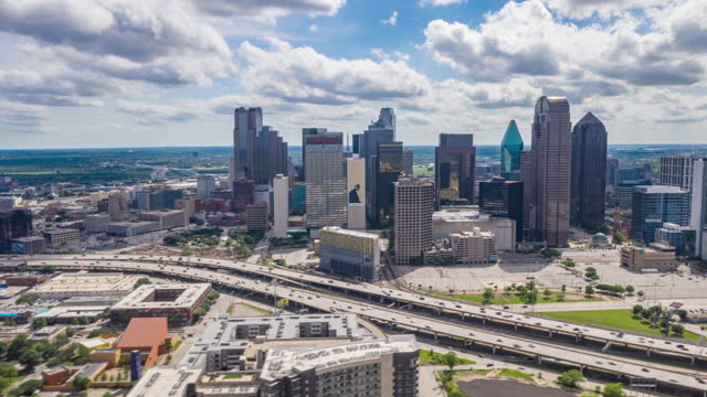 Stunning aerial hyper lapse footage of downtown area in Dallas, USA. Drone moving towards modern tall multi story commercial buildings behind rush highway