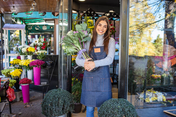 mujer de negocios apoyada en la puerta de la floristería. - florist small business flower shop owner fotografías e imágenes de stock