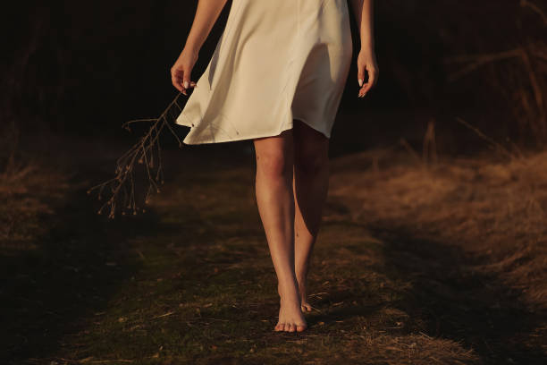 Lonely girl with a branch walks along the field and road stock photo