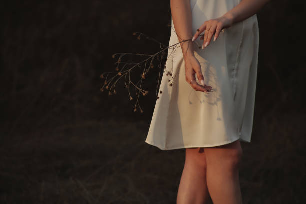 Lonely girl with a branch walks along the field and road stock photo