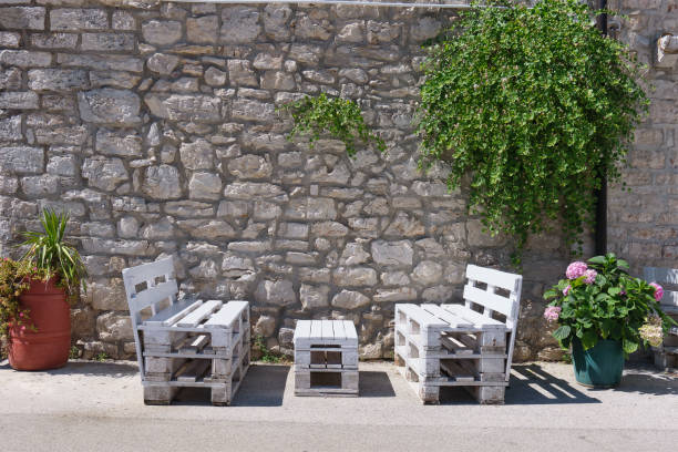 istock benches are situated beneath greenery in front of an historical stone wall between two flower pots 1318891516
