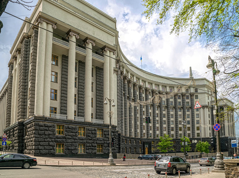 Kyiv, Ukraine - May 14, 2021: majestic facade of the building of the Cabinet of Ministers, the Government of Ukraine in the capital Kiev. A tall, pillared, horseshoe-shaped office building and traffic in downtown. Politics and Business in Europe