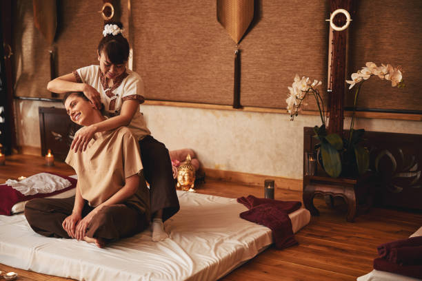massaggiaista tailandese che muove il palmo della mano lungo l'orecchio del cliente - massaging relaxation indoors traditional culture foto e immagini stock