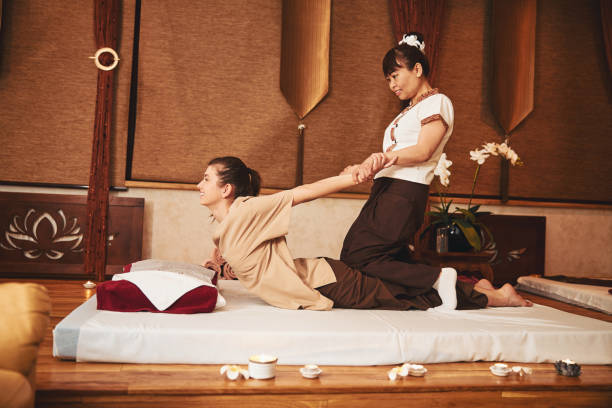 istock Thai masseuse sitting on woman and pulling her arms 1318897345