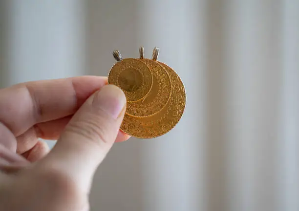Hand holding Turkish gold coin, Close up