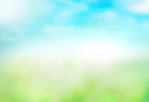 Green grass blue sky blurred bokeh background.Abstract spring summer nature backdrop,de focused illustration.Natural texture.