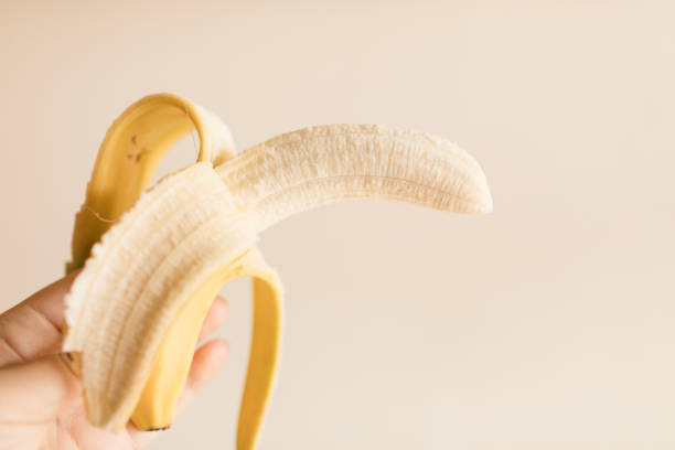 istock Ripe Yellow Banana Peeled Half Way with a Neutral Background 1318909096