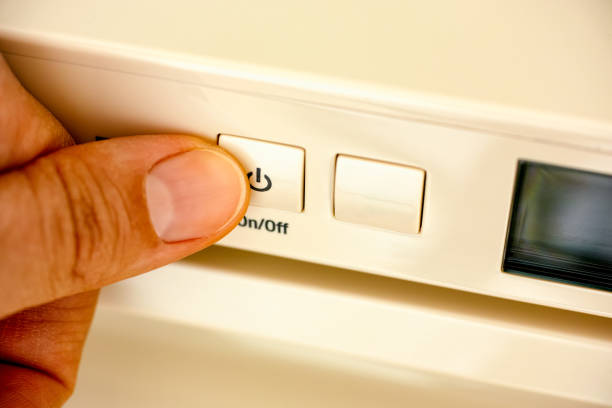 A Person finger pressing an on off button on a fridge