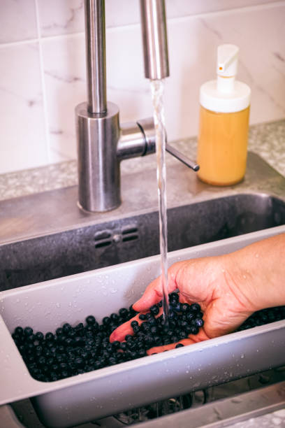 istock Person hand washing blueberries in kitchen sink. 1318914180