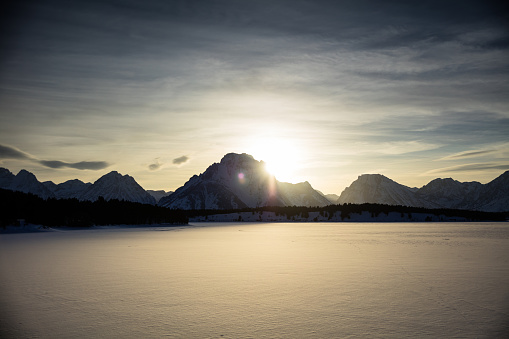 View across a frozen Jackson Lake towards the snow covered mountains of the Teton range in Grand Teton National Park in winter. Part of a sequence.