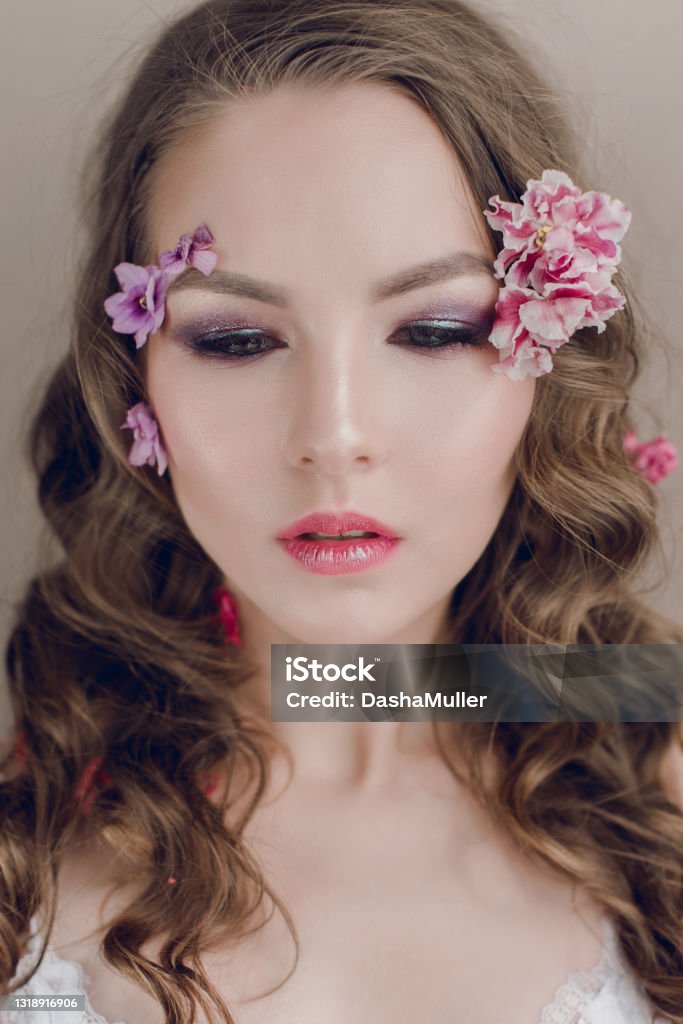 Cosmetics and manicure. Close-up portrait of attractive woman with dry flowers on her face and hair, pastel color, perfect make-up and skin on blue background. Fresh, trendy, spring retouched portrait Cosmetics and manicure. Close-up portrait of attractive woman with dry flowers on her face, pastel color, perfect make-up and skin. Fresh, trendy, spring retouched portrait Adult Stock Photo