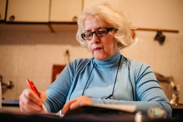 istock Senior old woman writing diary or book 1318918543