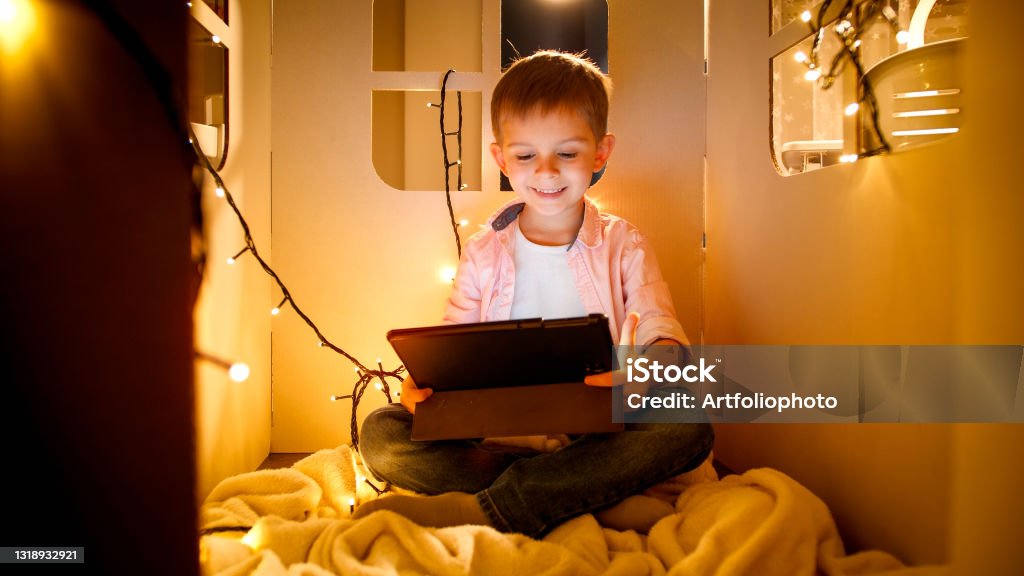 Foto de Feliz Sorrindo Menino Alegre Assistindo Desenhos Animados E Jogando  Jogos No Tablet Computador À Noite Conceito De Educação Infantil E Estudo À  Noite e mais fotos de stock de Criança 