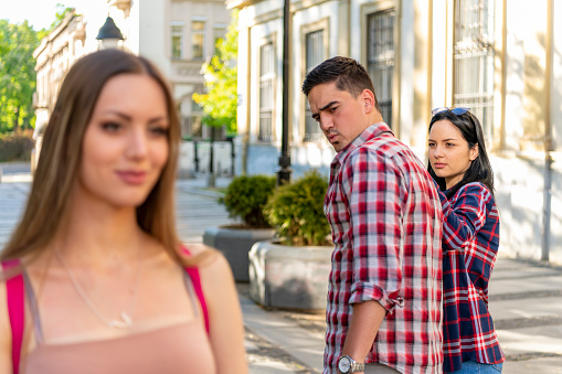 Concepto de infidelidad. Un hombre mujeriego infiel dando la vuelta sorprendido por otra mujer mientras caminaba con su novia en la calle photo