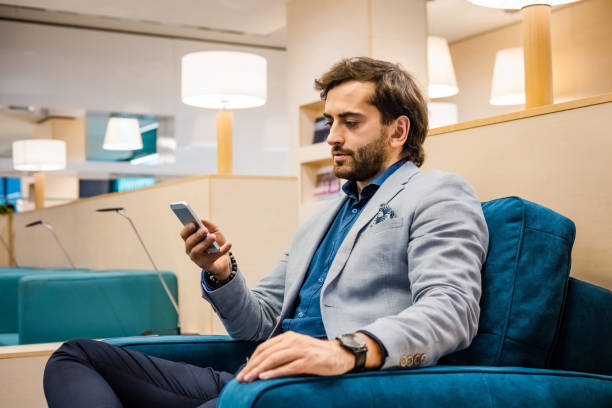 istock Businessman using mobile phone at airport lounge 1318936244
